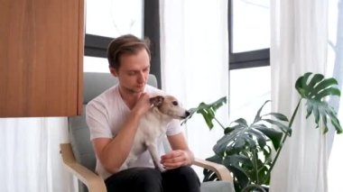 Gülümseyen adam koltukta safkan köpeği okşuyor.