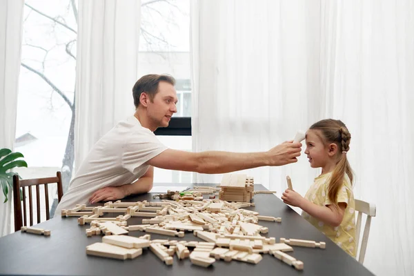 Father checking body temperature of daughter playing with wooden blocks — стоковое фото