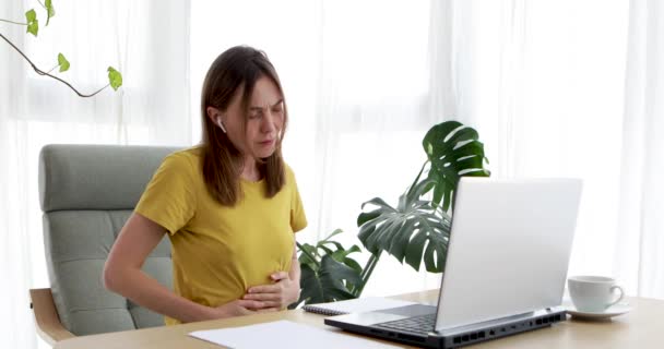 Woman working at home on laptop feels stomach pain — Stock Video