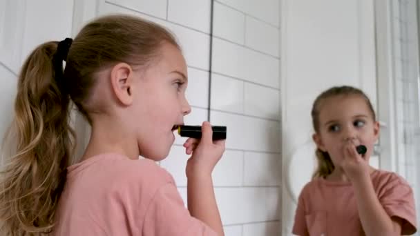 Маленька дівчинка малює губи помадою — стокове відео