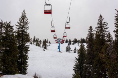 Çalışmayan eski bir kayak asansörünün boş kamaraları karlı bir yamacın arka planına karşı