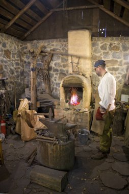 The blacksmith in the forge forges