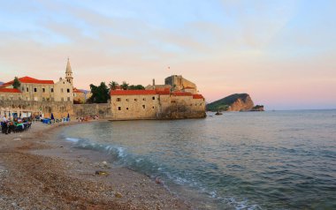 Karadağ 'da Budva Şatosu manzarası ve eski şehir plajı gün batımında