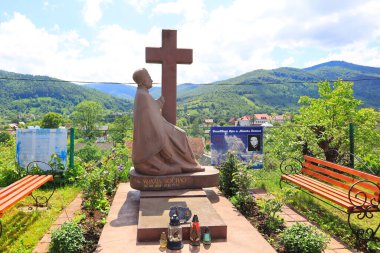 Priest's grave and panorama with mountains near wooden Church of Archstrategist Michael's Church in the village of Dora (suburb of Yaremche), Ukraine