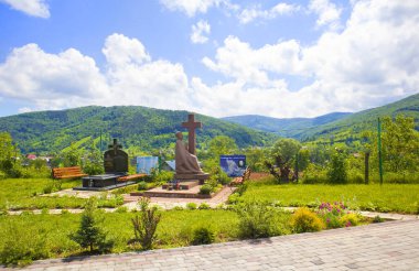 Priest's grave and panorama with mountains near wooden Church of Archstrategist Michael's Church in the village of Dora (suburb of Yaremche), Ukraine