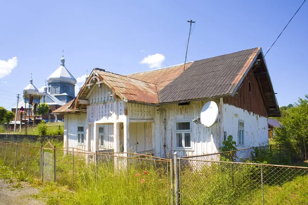 Old wooden house and Church of the Nativity of John the Baptist in  Kosiv, Ukraine