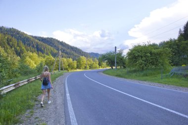 Girl is walking along of highway in the Carpathians in the Hutsul region, Ukraine