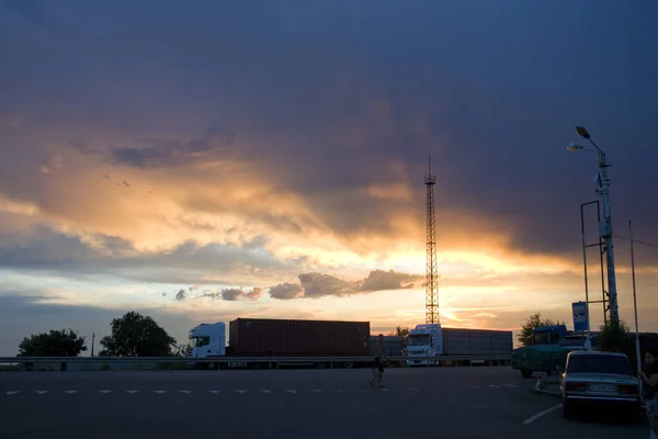 Road with large trucks against the backdrop of the sunset sky