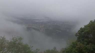Dağın tepesinden şehir, sis ve orman manzarası