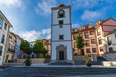 Luanco, Asturias, İspanya, 30 Mayıs 2021. Asturias 'taki Luanco şehrinde saat kulesi ve evler.