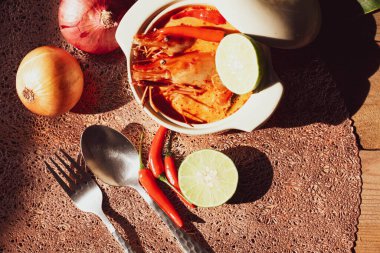 Tom Yum, karides ve nehir karidesli baharatlar ve biberli ve ahşap bir masaya yerleştirilmiş.