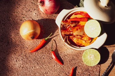 Tom Yum, karides ve nehir karidesli baharatlar ve biberli ve ahşap bir masaya yerleştirilmiş.