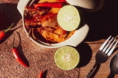 Tom Yum, karides ve nehir karidesli baharatlar ve biberli ve ahşap bir masaya yerleştirilmiş.