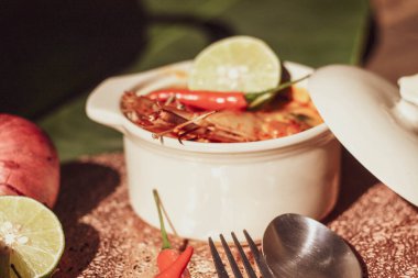 Tom Yum, karides ve nehir karidesli baharatlar ve biberli ve ahşap bir masaya yerleştirilmiş.
