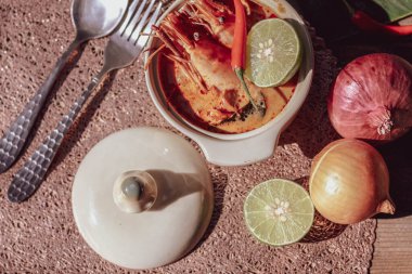 Tom Yum, karides ve nehir karidesli baharatlar ve biberli ve ahşap bir masaya yerleştirilmiş.