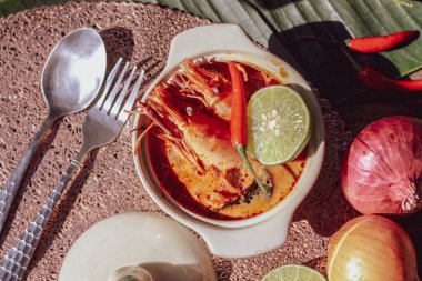 Tom Yum, karides ve nehir karidesli baharatlar ve biberli ve ahşap bir masaya yerleştirilmiş.