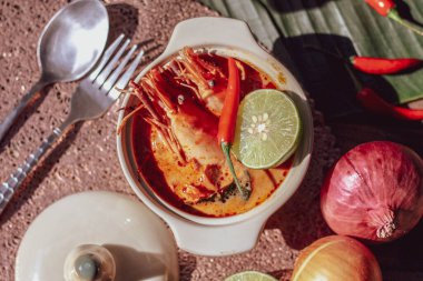 Tom Yum, karides ve nehir karidesli baharatlar ve biberli ve ahşap bir masaya yerleştirilmiş.