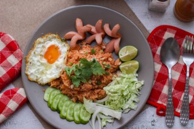 Amerikan pilavı sosis, salatalık, doğranmış sebze ile servis edilir. Tayland baharatlı beyaz bir masada gri bir tabakta..