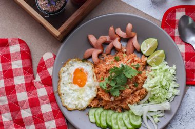 Amerikan pilavı sosis, salatalık, doğranmış sebze ile servis edilir. Tayland baharatlı beyaz bir masada gri bir tabakta..