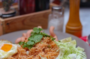 Amerikan pilavı sosis, salatalık, doğranmış sebze ile servis edilir. Tayland baharatlı beyaz bir masada gri bir tabakta..