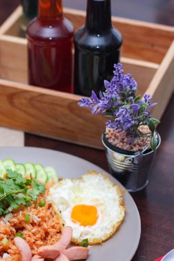 Kızarmış sosis, salatalık, doğranmış sebzeler ile servis edilen Amerikan pilavı kahverengi ahşap bir masada, Tayland soslu..