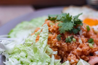 Kızarmış sosis, salatalık, doğranmış sebzeler ile servis edilen Amerikan pilavı kahverengi ahşap bir masada, Tayland soslu..