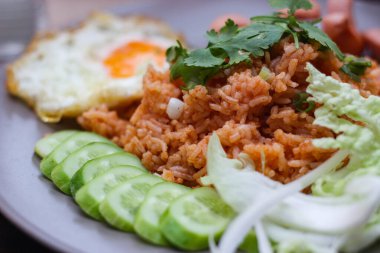 Kızarmış sosis, salatalık, doğranmış sebzeler ile servis edilen Amerikan pilavı kahverengi ahşap bir masada, Tayland soslu..