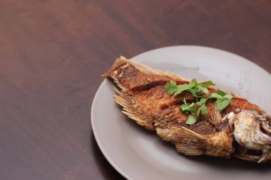 Kızarmış tilapia tam kıvamındaydı. Tayland 'da bir restoranda kahverengi ahşap bir masada gri işler yapmış..