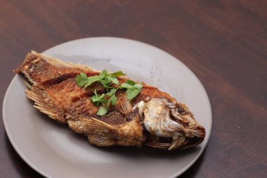 Kızarmış tilapia tam kıvamındaydı. Tayland 'da bir restoranda kahverengi ahşap bir masada gri işler yapmış..