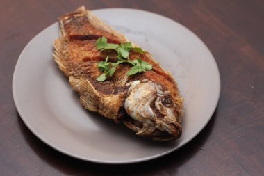 Kızarmış tilapia tam kıvamındaydı. Tayland 'da bir restoranda kahverengi ahşap bir masada gri işler yapmış..