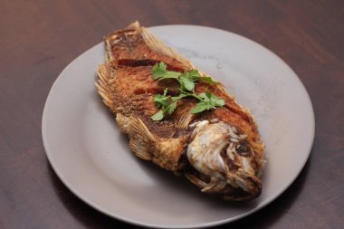 Kızarmış tilapia tam kıvamındaydı. Tayland 'da bir restoranda kahverengi ahşap bir masada gri işler yapmış..
