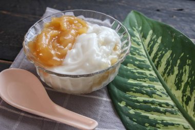 Hindistancevizi kremalı tatlı pirinç eriştesi siyah ahşap bir masada cam bir fincanda servis edilir..