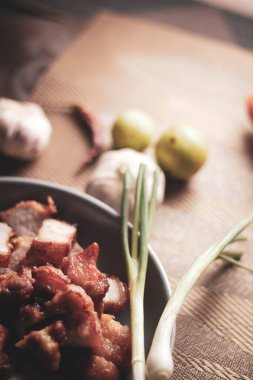 Balık soslu kızarmış domuz eti, siyah ahşap zeminde gri bir tabakta servis edilir..