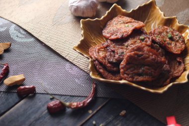 Siyah ahşap bir masaya konmuş yaprak şeklinde bir tabakta servis edilen kızarmış balık ezmesi topları..