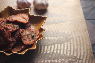 Siyah ahşap bir masaya konmuş yaprak şeklinde bir tabakta servis edilen kızarmış balık ezmesi topları..