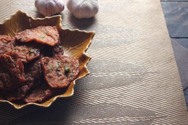 Siyah ahşap bir masaya konmuş yaprak şeklinde bir tabakta servis edilen kızarmış balık ezmesi topları..
