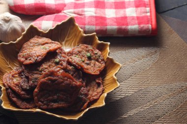 Siyah ahşap bir masaya konmuş yaprak şeklinde bir tabakta servis edilen kızarmış balık ezmesi topları..