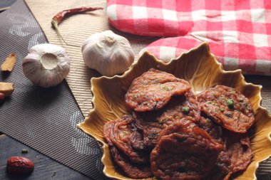 Siyah ahşap bir masaya konmuş yaprak şeklinde bir tabakta servis edilen kızarmış balık ezmesi topları..