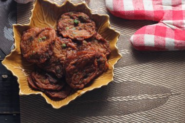 Siyah ahşap bir masaya konmuş yaprak şeklinde bir tabakta servis edilen kızarmış balık ezmesi topları..