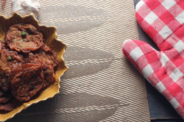 Siyah ahşap bir masaya konmuş yaprak şeklinde bir tabakta servis edilen kızarmış balık ezmesi topları..