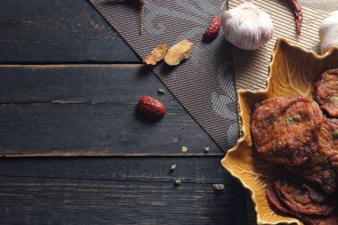 Siyah ahşap bir masaya konmuş yaprak şeklinde bir tabakta servis edilen kızarmış balık ezmesi topları..