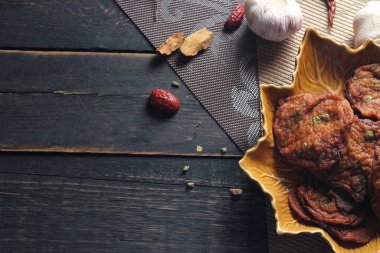 Siyah ahşap bir masaya konmuş yaprak şeklinde bir tabakta servis edilen kızarmış balık ezmesi topları..