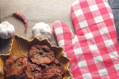 Siyah ahşap bir masaya konmuş yaprak şeklinde bir tabakta servis edilen kızarmış balık ezmesi topları..