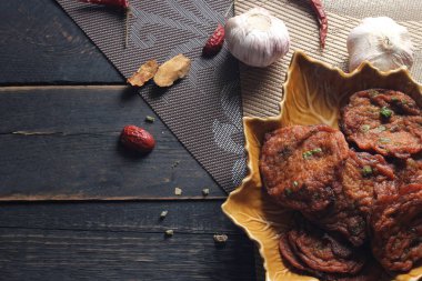 Siyah ahşap bir masaya konmuş yaprak şeklinde bir tabakta servis edilen kızarmış balık ezmesi topları..