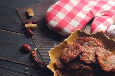 Siyah ahşap bir masaya konmuş yaprak şeklinde bir tabakta servis edilen kızarmış balık ezmesi topları..