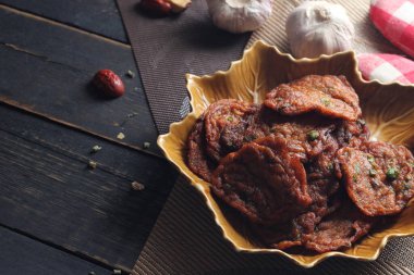 Siyah ahşap bir masaya konmuş yaprak şeklinde bir tabakta servis edilen kızarmış balık ezmesi topları..