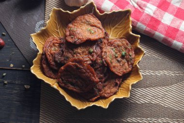 Siyah ahşap bir masaya konmuş yaprak şeklinde bir tabakta servis edilen kızarmış balık ezmesi topları..