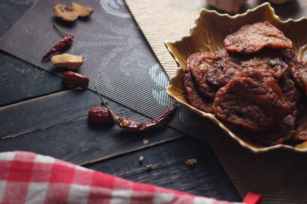 Siyah ahşap bir masaya konmuş yaprak şeklinde bir tabakta servis edilen kızarmış balık ezmesi topları..