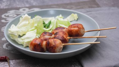 Izgara mayalanmış domuz eti ve gri tabakta yapışkan pirinç sosisi..