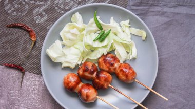 Izgara mayalanmış domuz eti ve gri tabakta yapışkan pirinç sosisi..